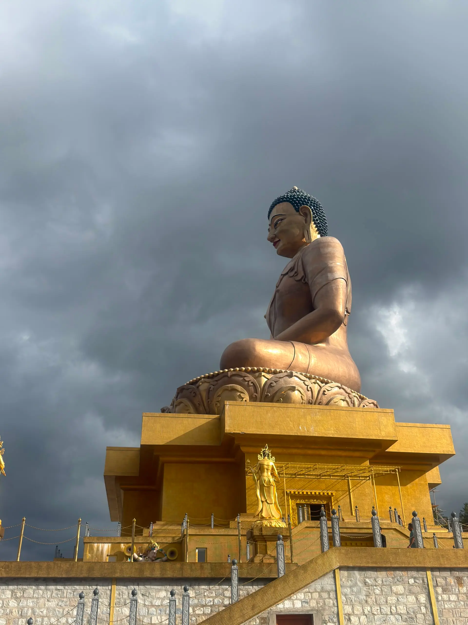 The Great Buddha Dordenma, a giant gilded seated Buddha, against a stormy sky above Thimphu
