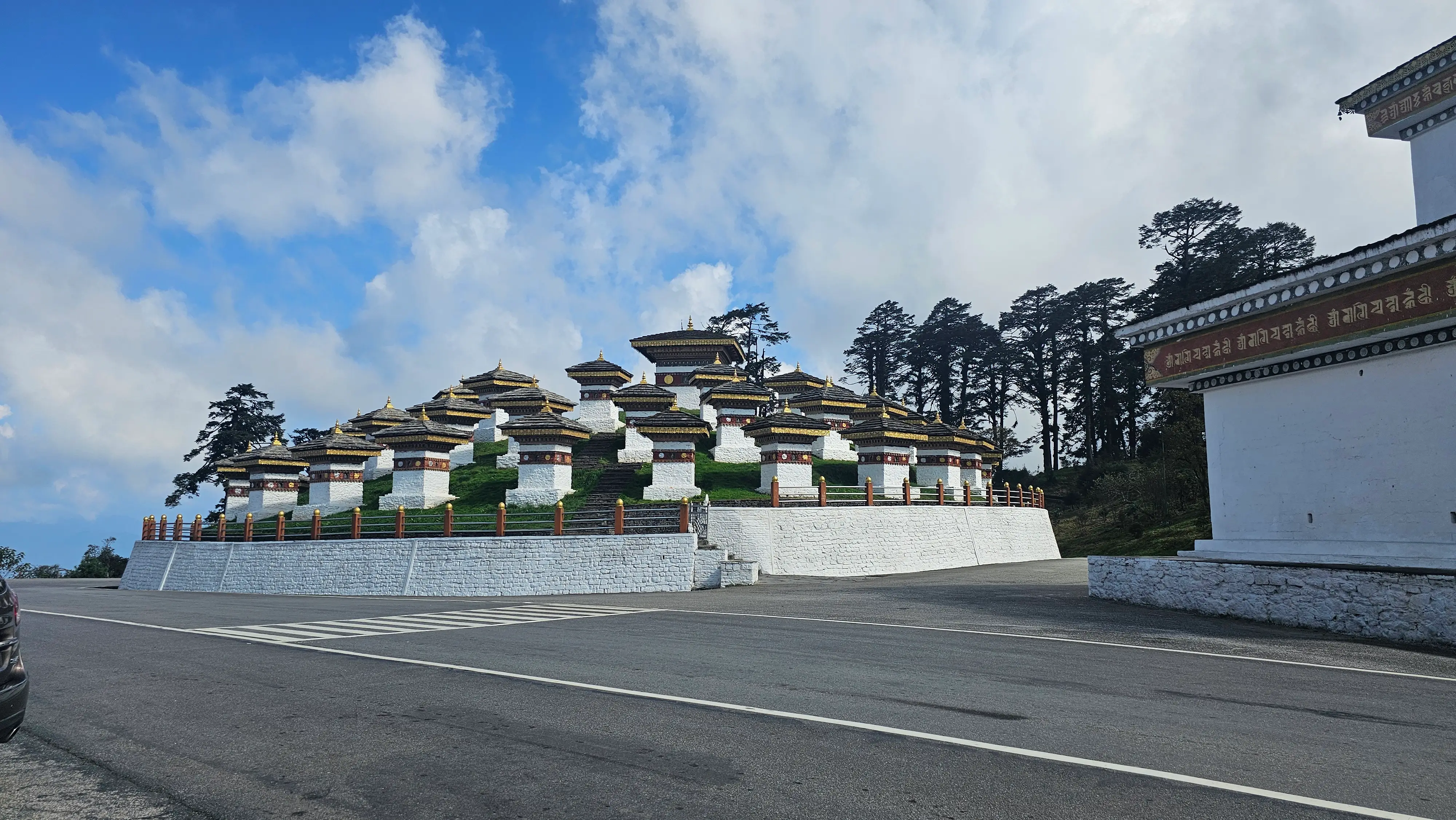 The 108 memorial chortens at Dochula Pass under a bright blue sky in Bhutan