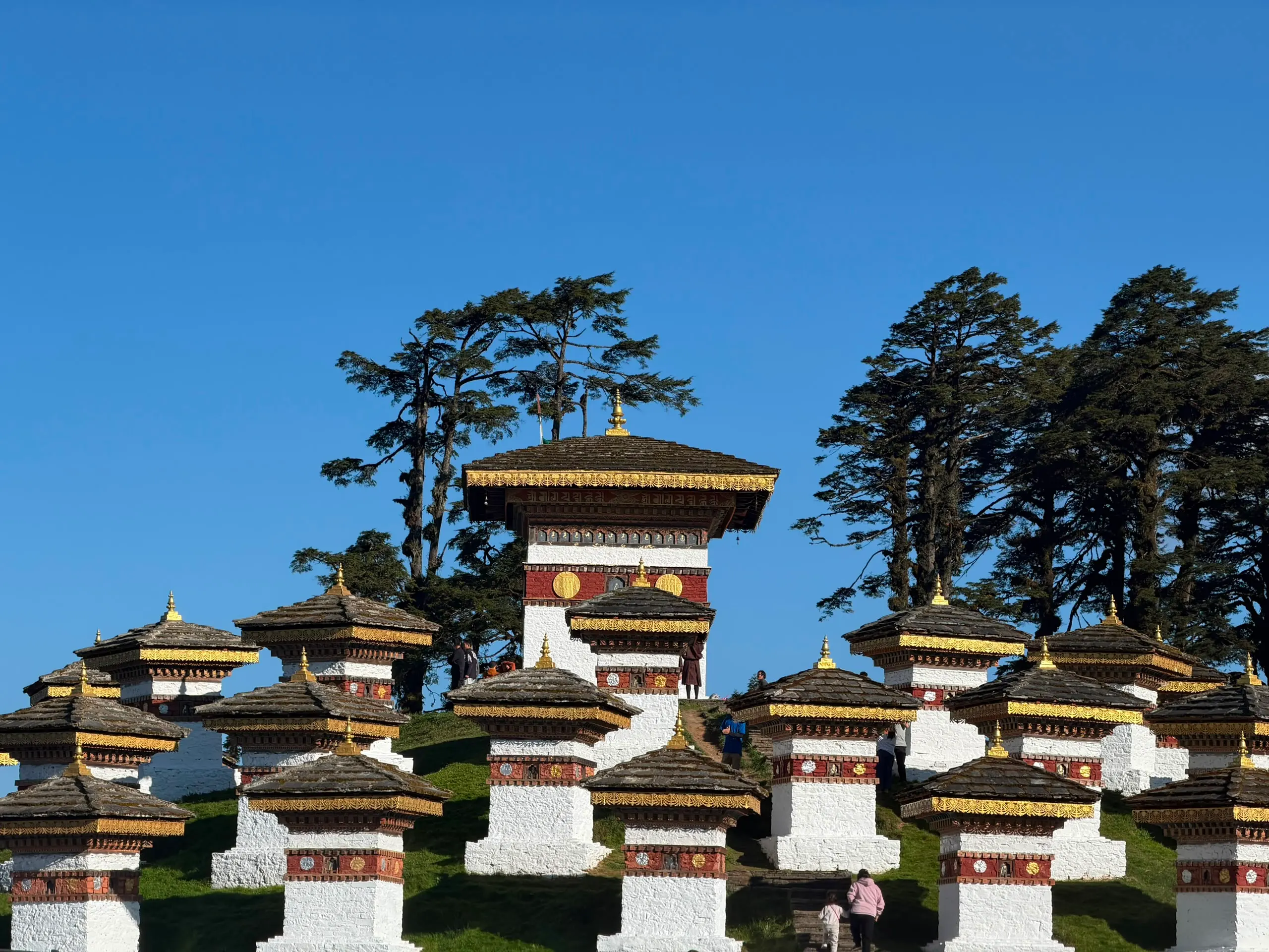 The Druk Wangyal 108 chortens at Dochula Pass under a blue sky