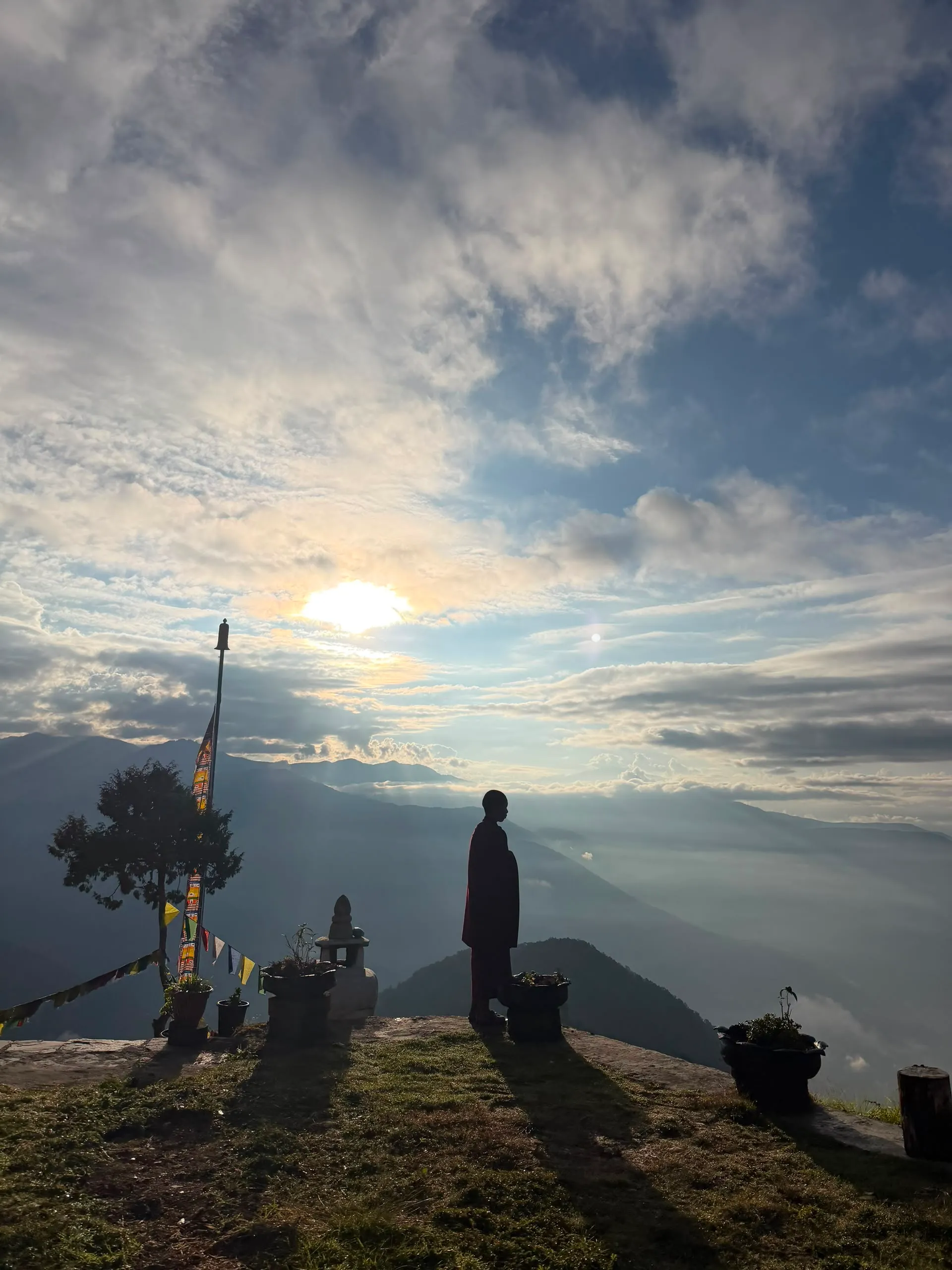 A monk on a mountain ridge at sunrise above the clouds