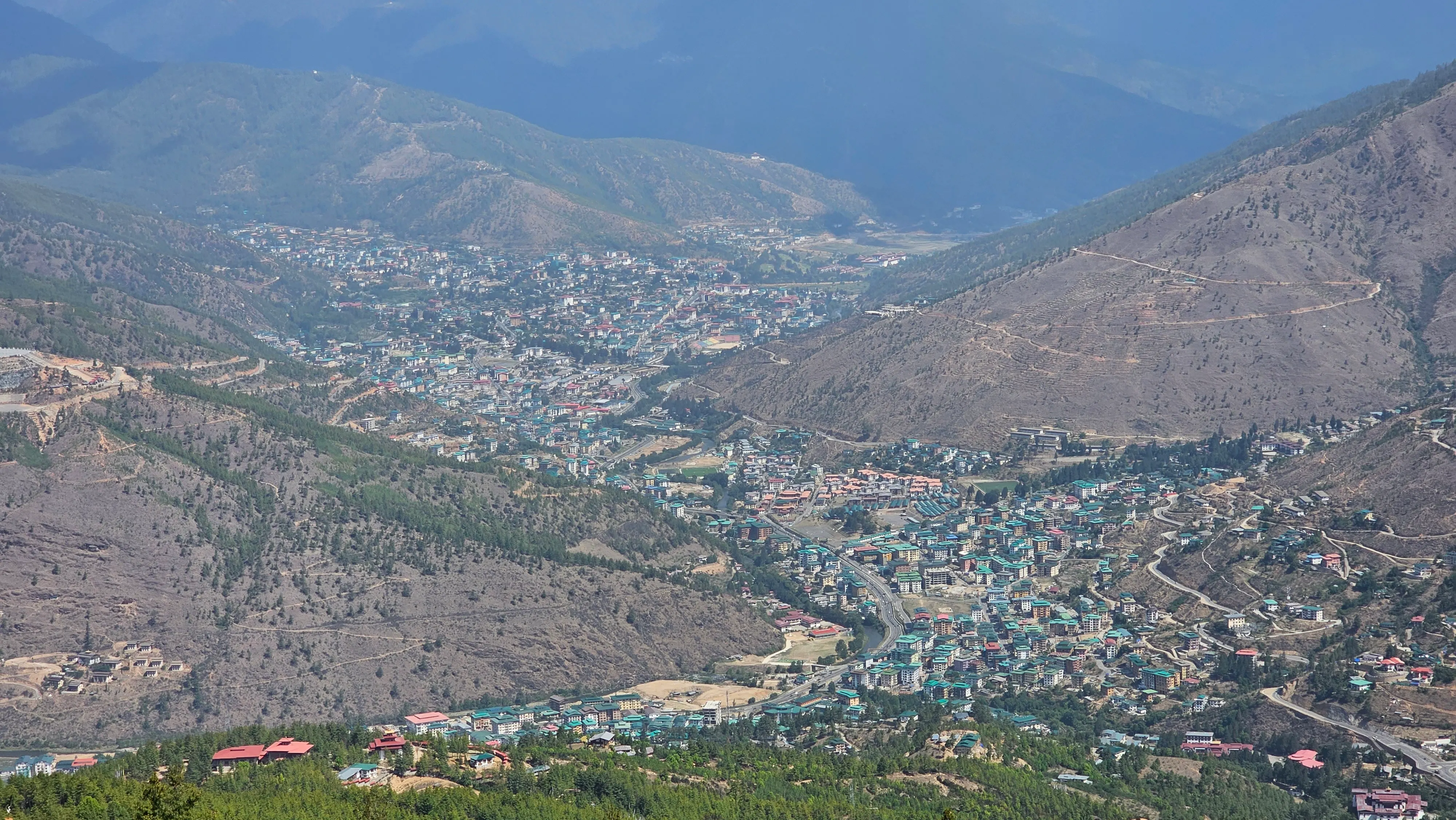 An aerial view of a Bhutanese town filling a green mountain valley